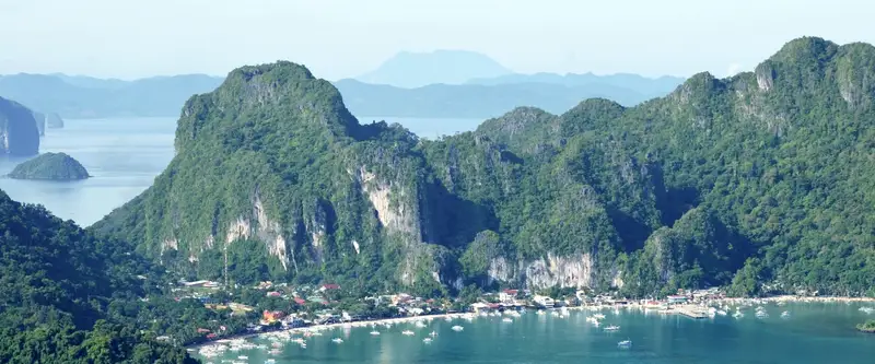 baie d'El Nido, à Palawan, bordée de falaises boisées, bateaux au mouillage