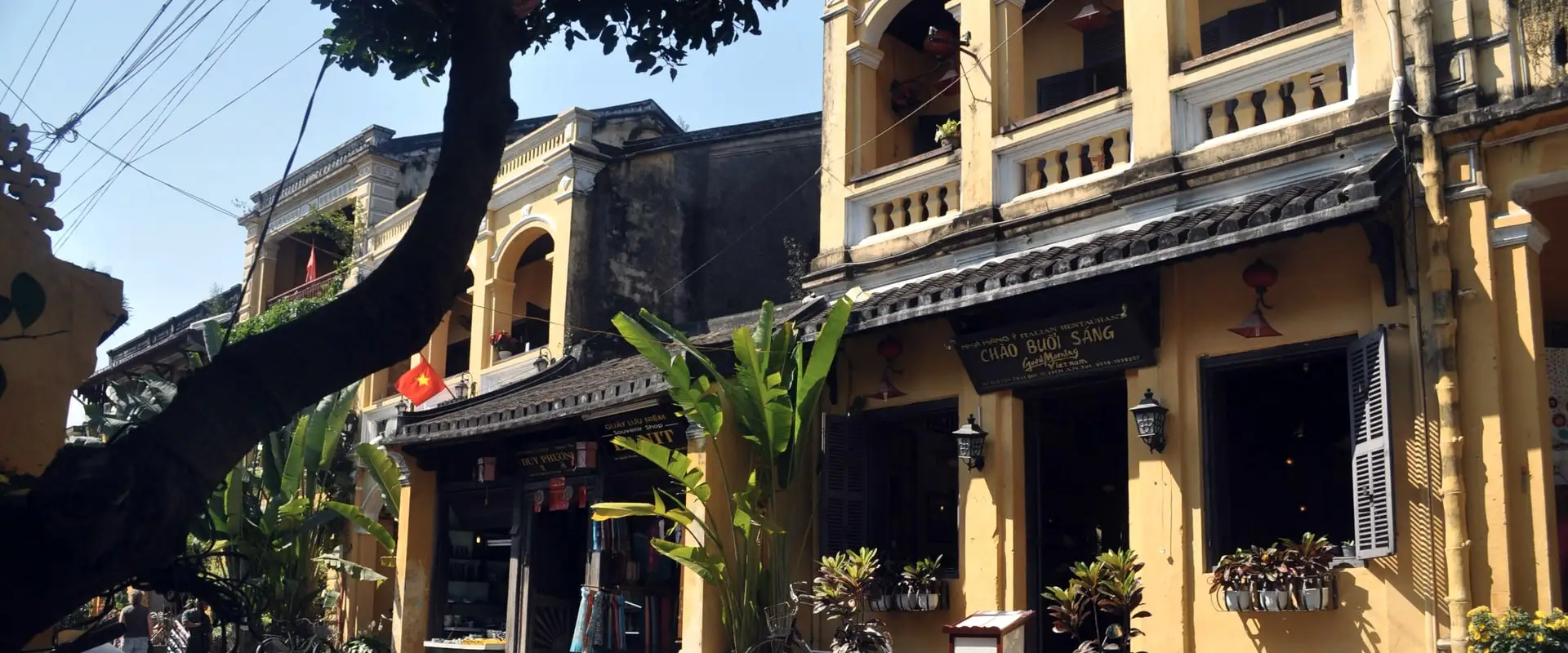 façades jaunes à volets de bois dans la vieille ville de Hội An, motos garées le long de la rue