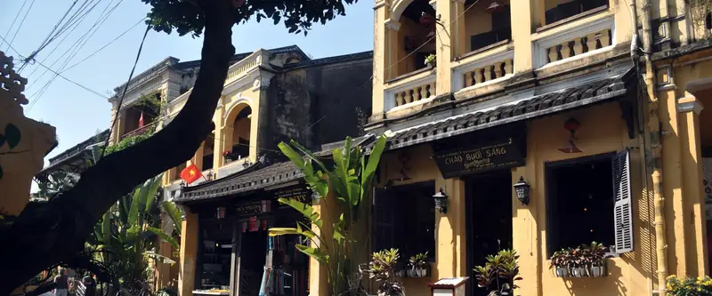 façades jaunes à volets de bois dans la vieille ville de Hội An, motos garées le long de la rue