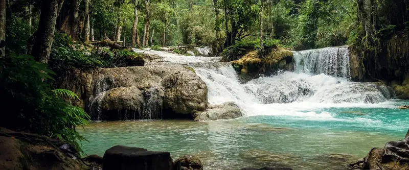 eau turquoise et cascades en gradins de Kuang Si, au milieu de la forêt